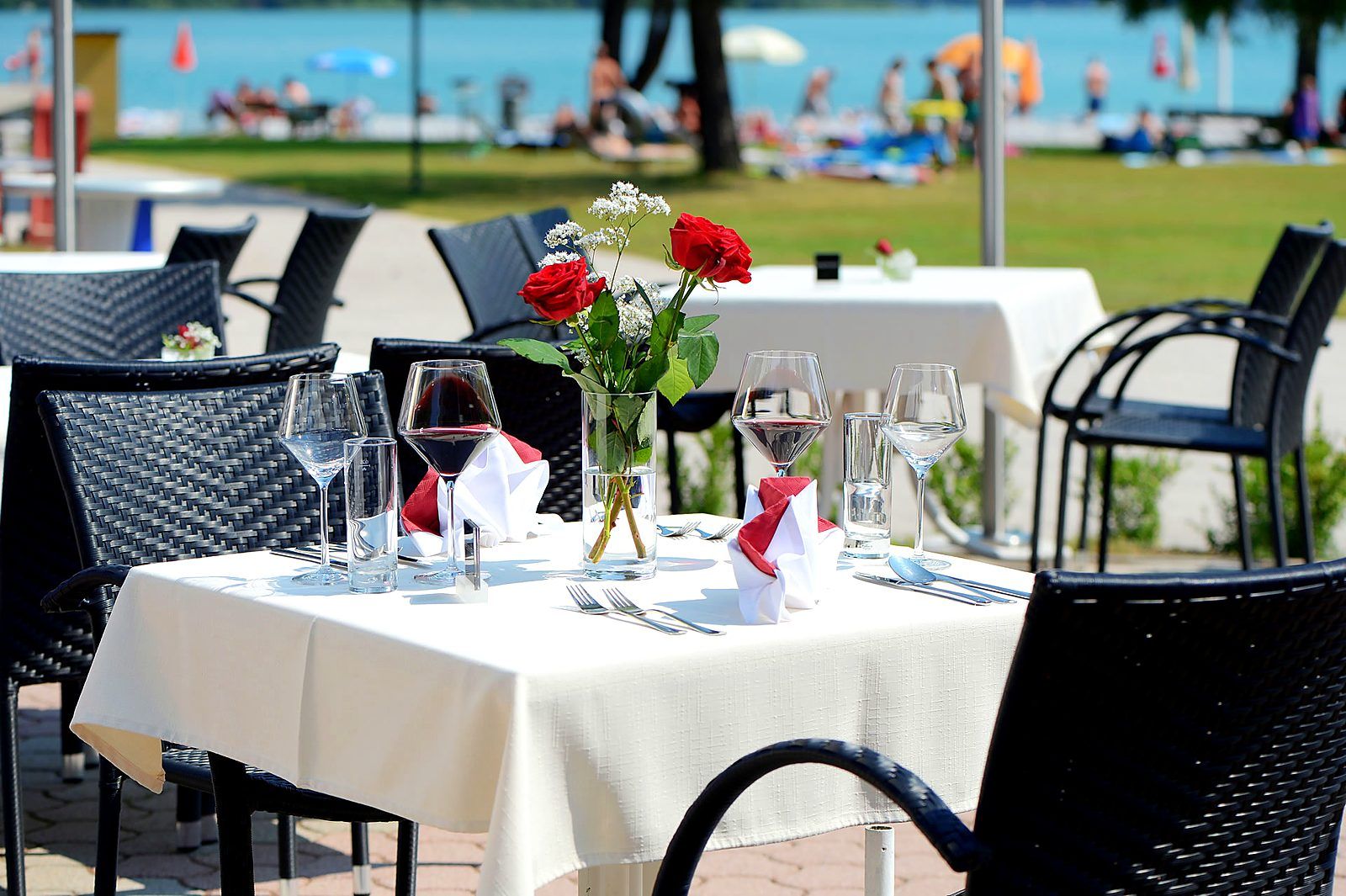 Gedeckter Tisch auf der Terrasse des See-Restaurants mit Blick auf den Faaker See